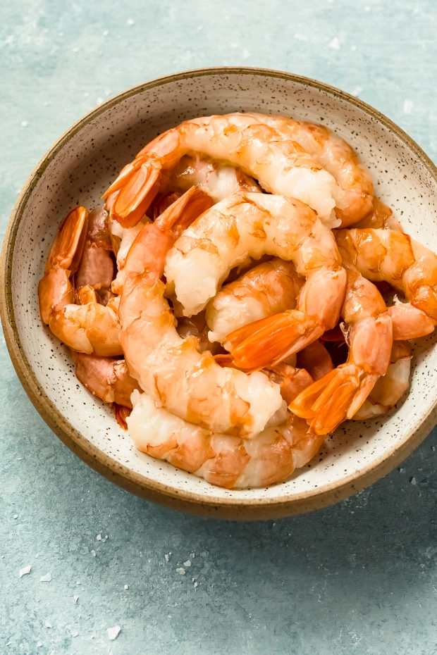 Angled photo of peeled and deveined shrimp in a bowl - prep shot for the recipe.