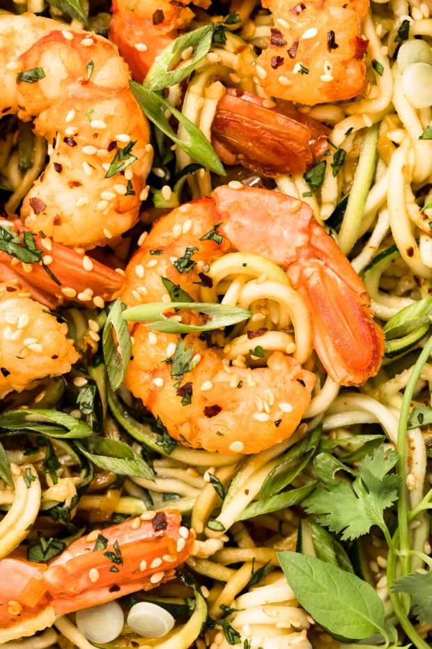 Overhead, close-up photo of stir fry shrimp on top of zucchini vegetable noodles.