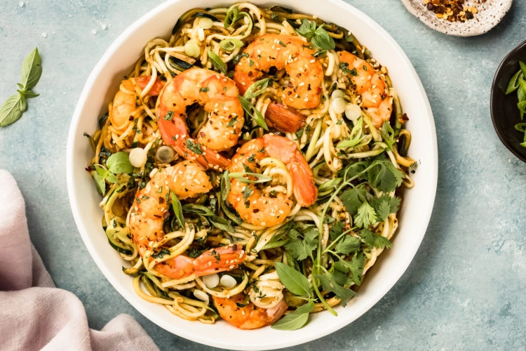 Overhead photo of Zucchini Vegetable Noodle Stir Fry with shrimp in a white serving bowl.