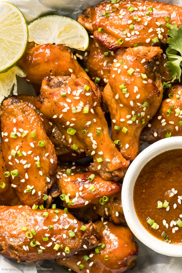 Overhead, close-up photo of Crockpot Soy Sauce Chicken Wings garnished with sesame seeds, scallions and chives. 