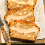 Overhead photo of slices of Cinnamon Apple Bread on a parchment paper lined wood cutting board.