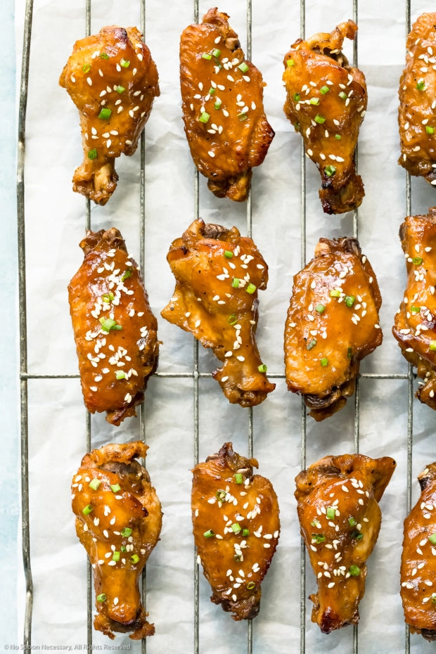 Overhead photo of sticky Chinese wings on a wire baking rack. 