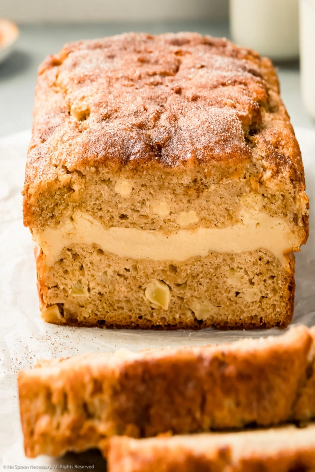 Angled photo of an apple bread loaf that has been cut into to expose the interior and the cream cheese filling.