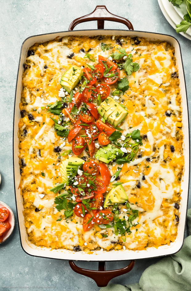 Overhead photo of Mexican Casserole garnished with chopped cherry tomatoes, sliced avocados and fresh cilantro.