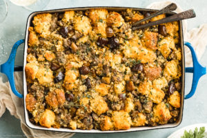 Overhead photo of Chestnut Stuffing in a blue baking dish with serving spoons inserted into the stuffing.