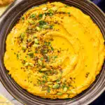 Overhead photo of sweet potato hummus in a large serving bowl with pita chips.