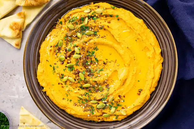 Overhead photo of sweet potato hummus in a large serving bowl with pita chips.