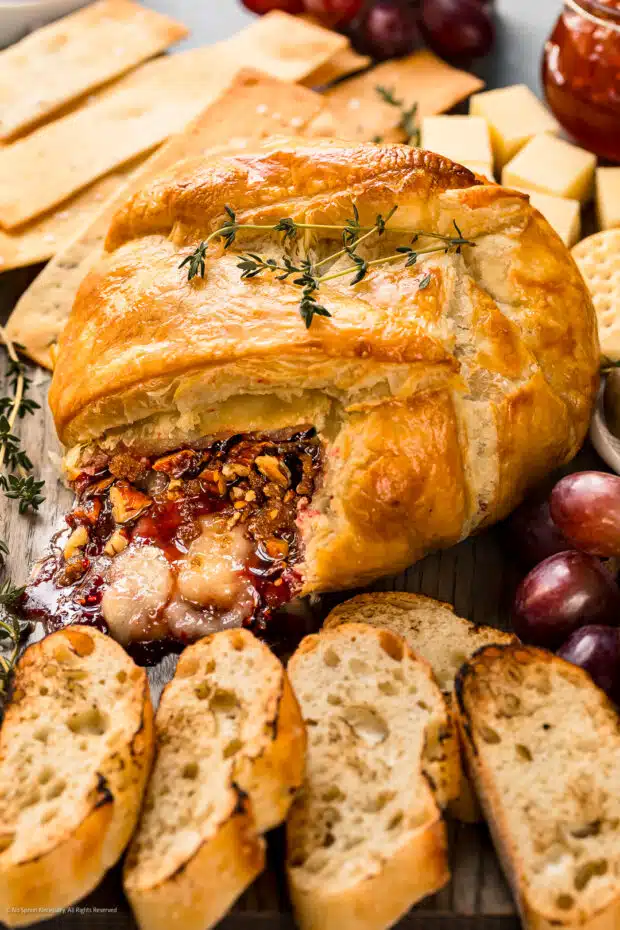 Straight on photo of a baked brie en croute with raspberries.