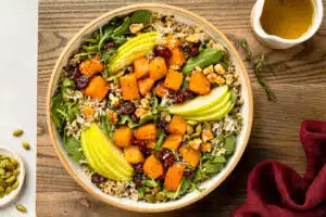 Overhead photo of butternut squash salad with apples, cranberries and rice in a white bowl.