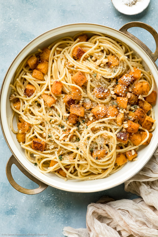 Overhead photo of spaghetti pasta tossed with brown butter sauce, sautéed butternut squash cubes, parmesan, toasted walnuts and fresh thyme in a large skillet - photo of step 4 of the recipe.