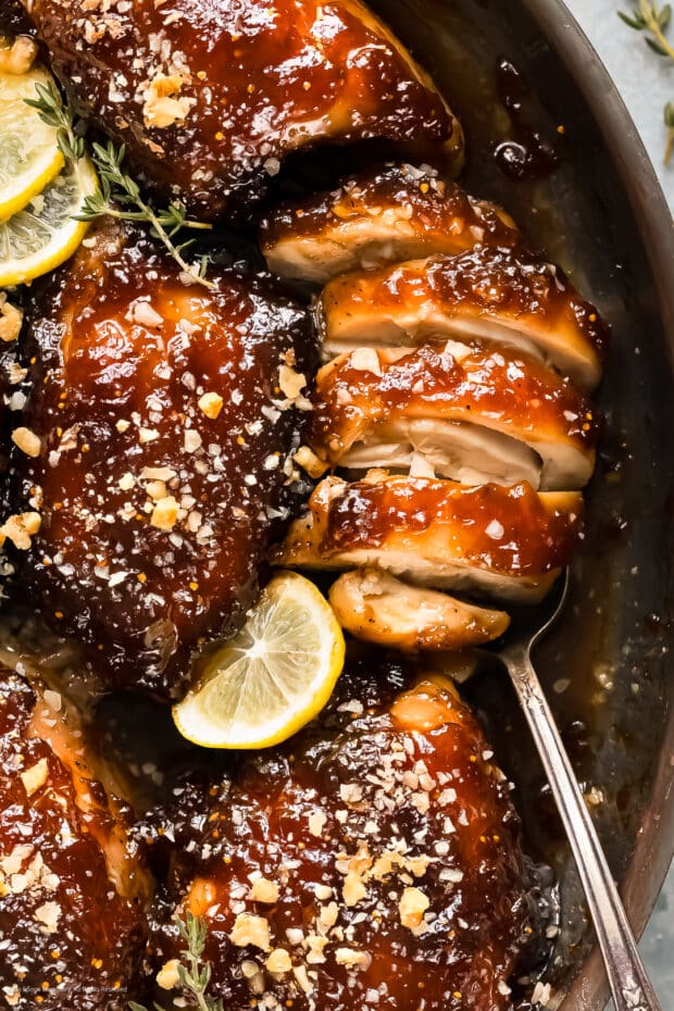 Close-up photo of a cooked and sliced chicken thigh with fig sauce.