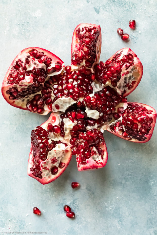Overhead photo of a cut into pomegranate showcasing the arils inside the fruit - photo of one of the main ingredients in the recipe.