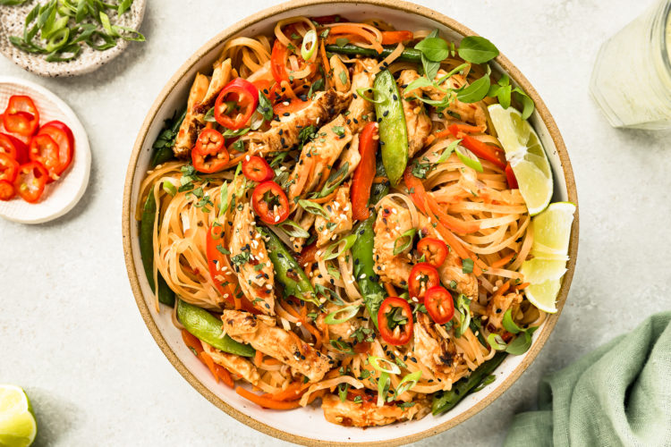 Overhead photo of Chinese Chicken with Stir-Fry Vegetables and noodles in a white serving bowl.