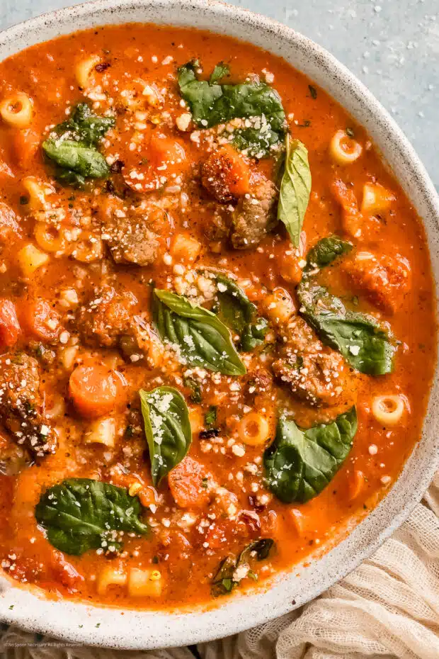 Close-up photo of Italian sausage in soup with pasta and veggies.