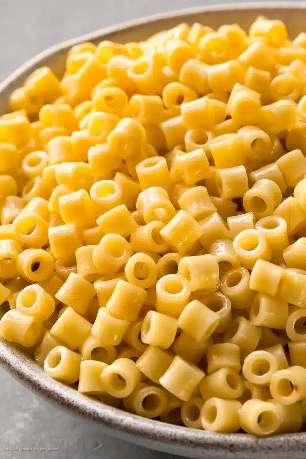 Close-up photo of cooked tiny tubular pasta in a bowl. 