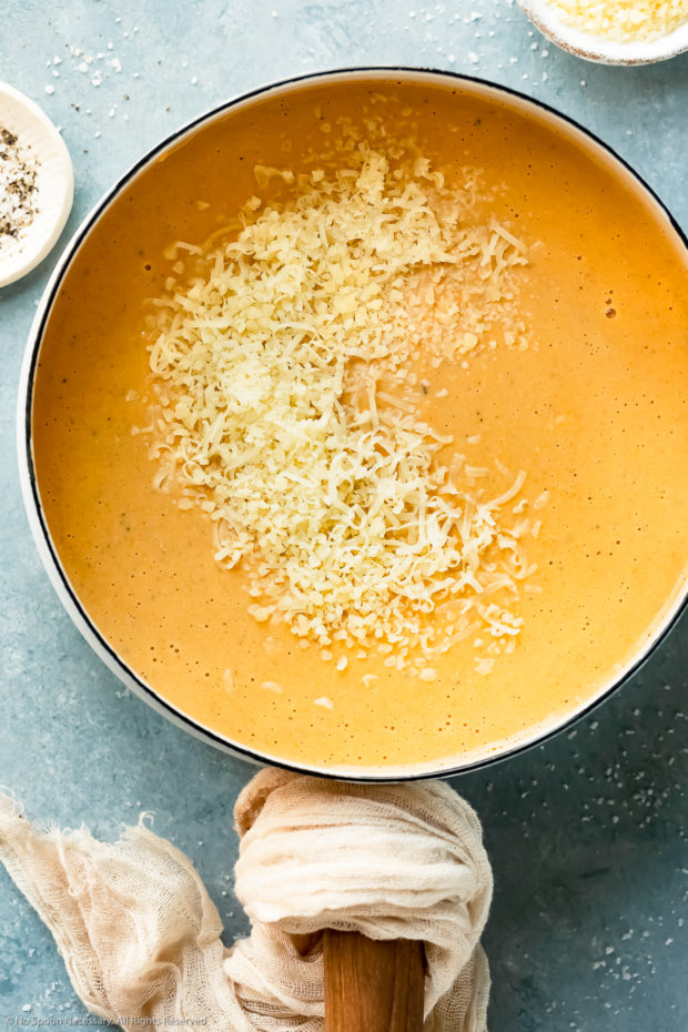 Overhead photo of butternut squash sauce with freshly grated cheese scattered on top of the sauce - photo of healthy cheese sauce before stirring.