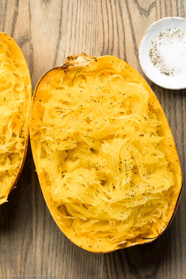 Overhead photo of a half of a roasted spaghetti squash that has been scraped with a fork to showcase the spaghetti-like strands.