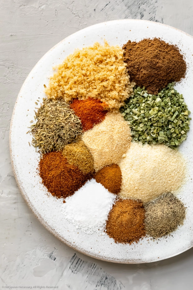 Overhead photo of all the spices in Jerk Seasoning neatly organized on a white plate with the name of each individual spice written out.