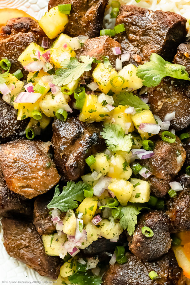 Overhead, up-close photo of Jamaican Jerk Pork topped with tropical salsa and fresh cilantro.