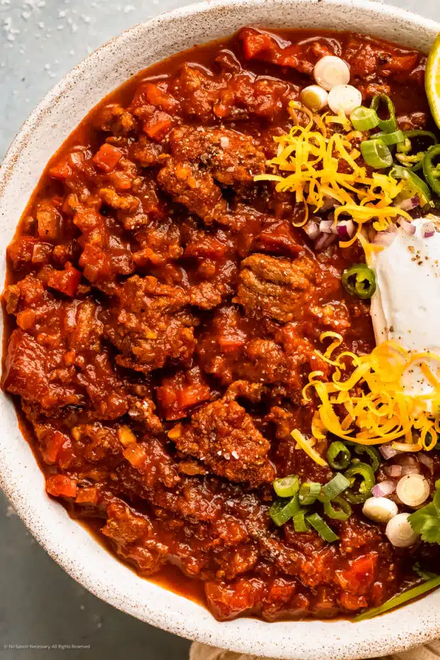 Photo of chili without beans recipe topped with sour cream, cheddar cheese and cilantro.