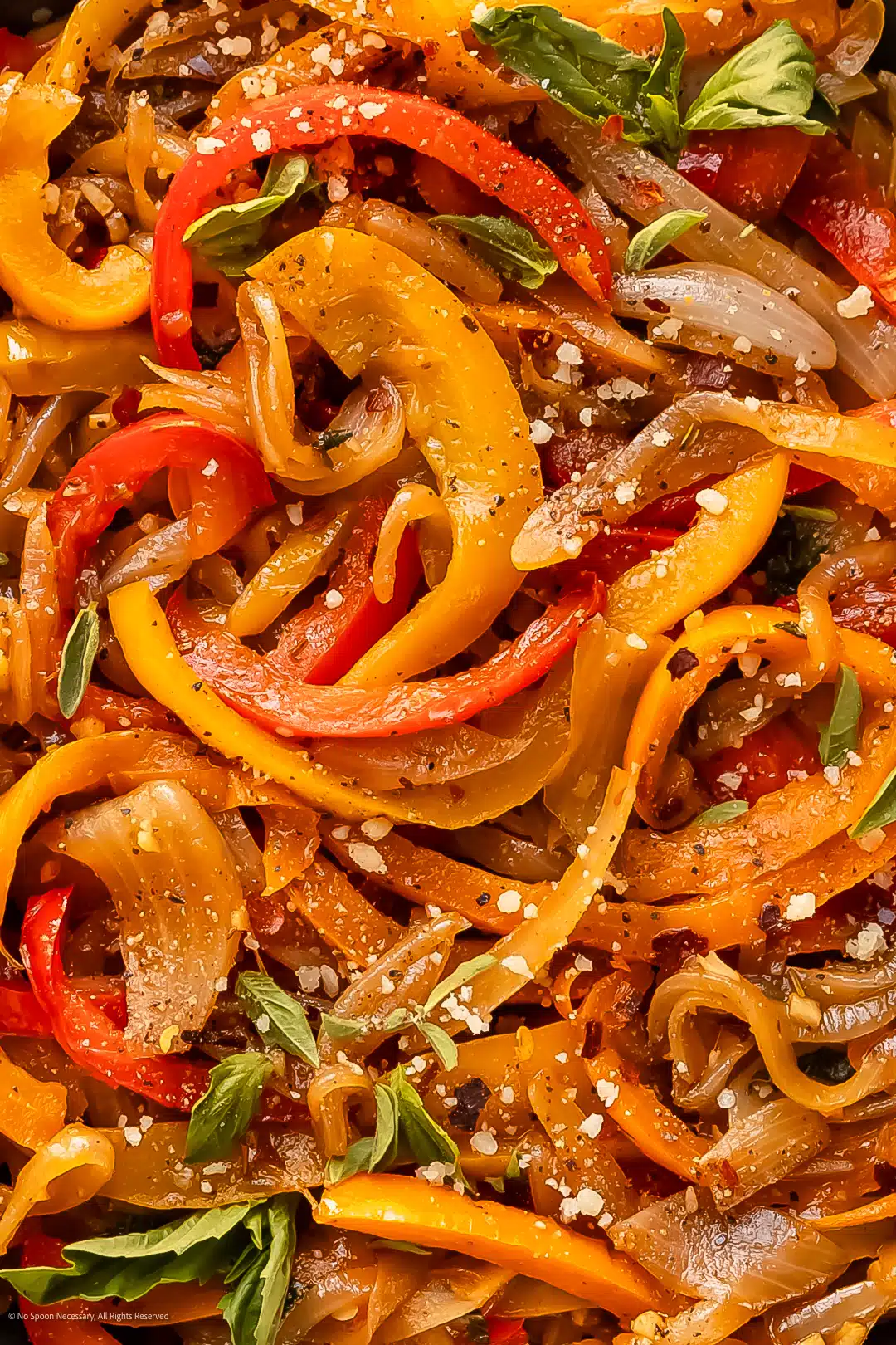 Close-up photo showcasing the tender texture of peppers and onions sauteed on the stovetop.