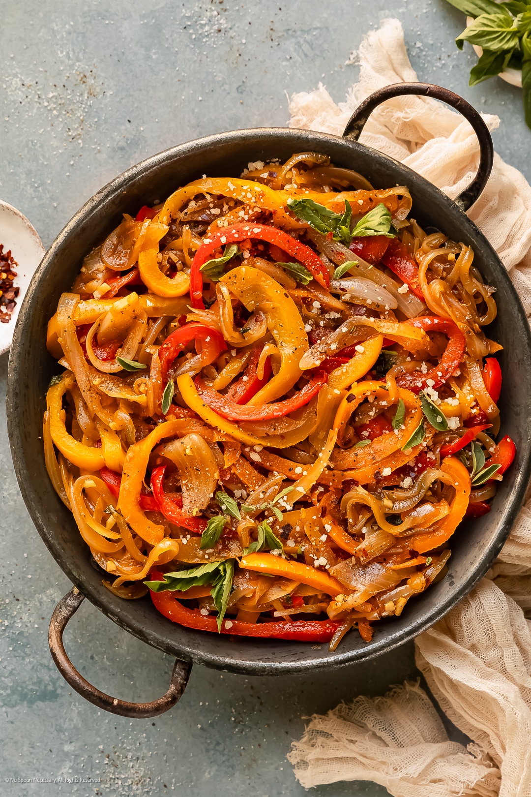 Overhead photo sautéed onions and peppers with garlic and italian seasonings in a large frying pan.