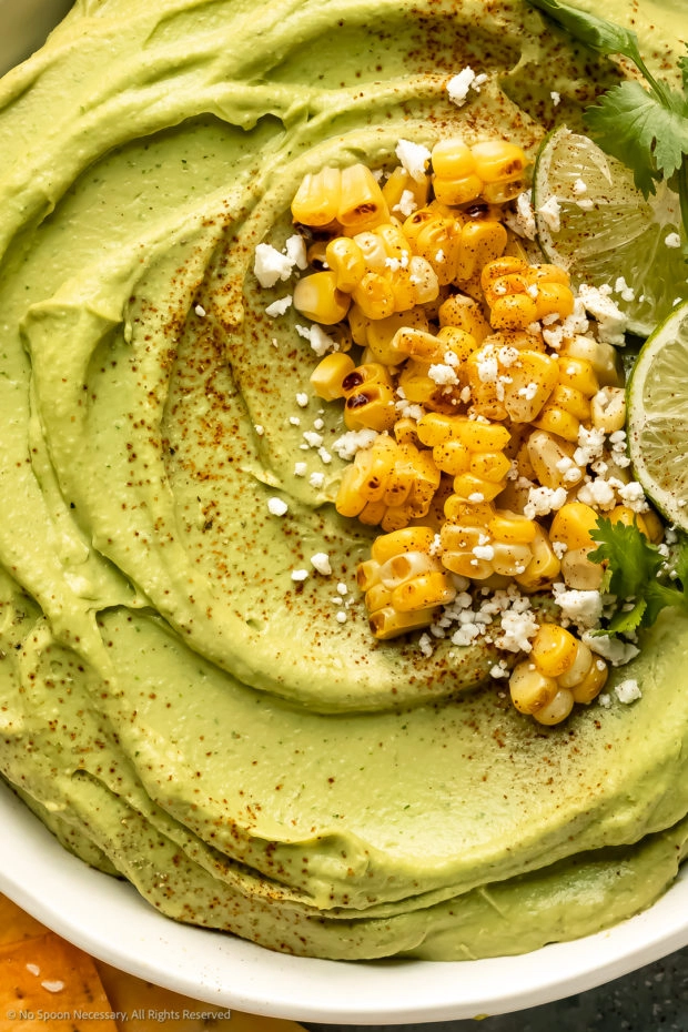 Overhead close-up photo of spicy hummus dip topped with corn kernels. 