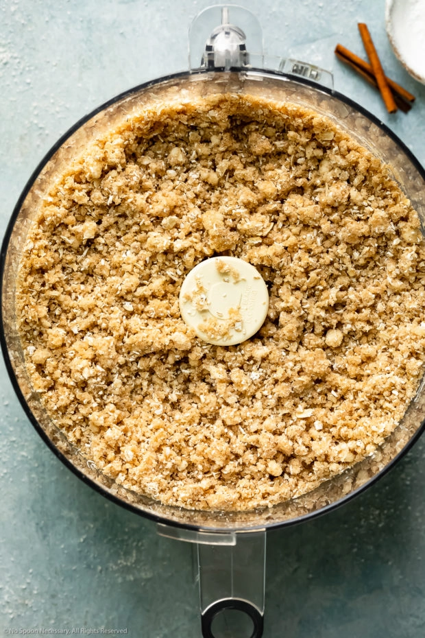 Overhead photo of homemade cinnamon oat crumble (streusel) in the bowl of a food processor