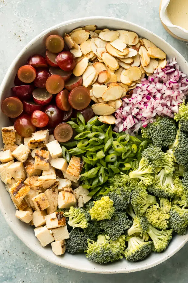 Overhead photo of all the ingredients in broccoli salad with grapes neatly arranged in a large mixing bowl.