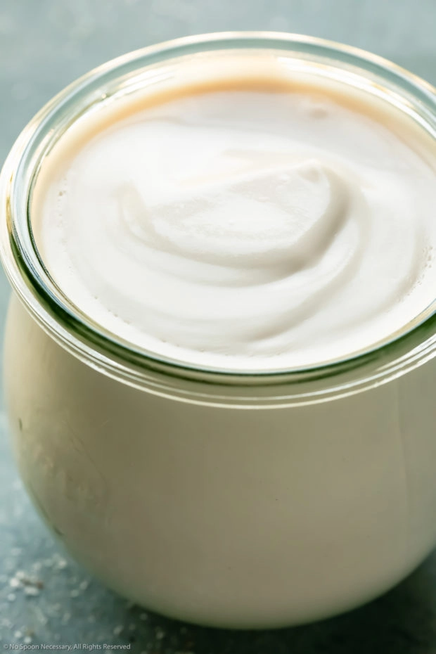 Angled, up-close photo of coconut milk in a small glass jar - photo of the main ingredient in the recipe.