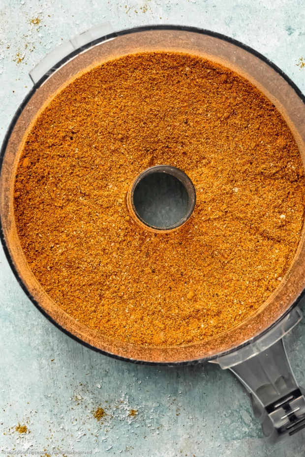 Overhead photo of BBQ dry rub seasonings in the bowl of a food processor after being ground together to create a fine powder.