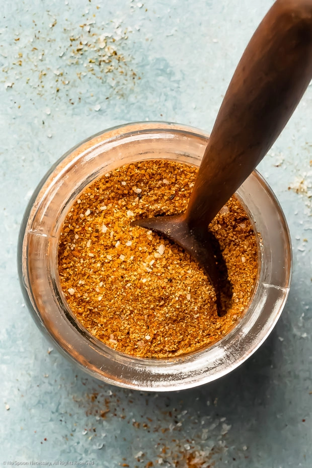 Overhead photo of BBQ spice rub in a glass jar with a spoon inserted into the rub.