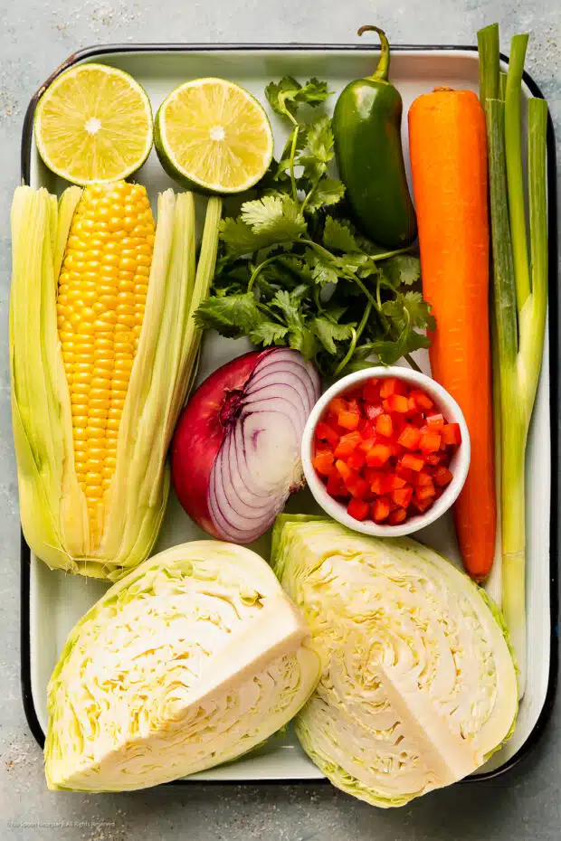 Overhead photo of the ingredients for mexican cabbage slaw recipe on a white tray.