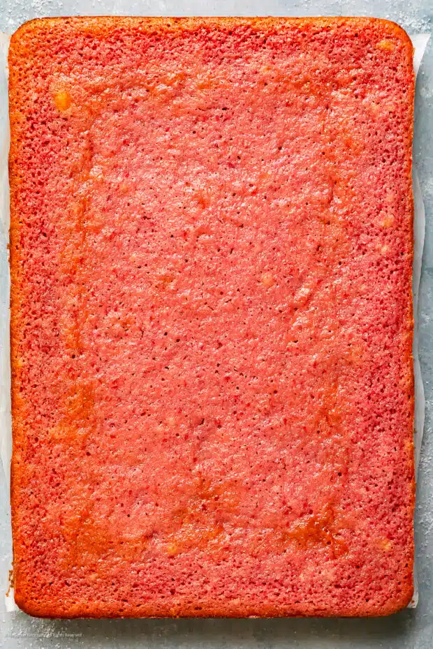 Close-up photo of a from scratch strawberry cake cooling on a piece of parchment paper.