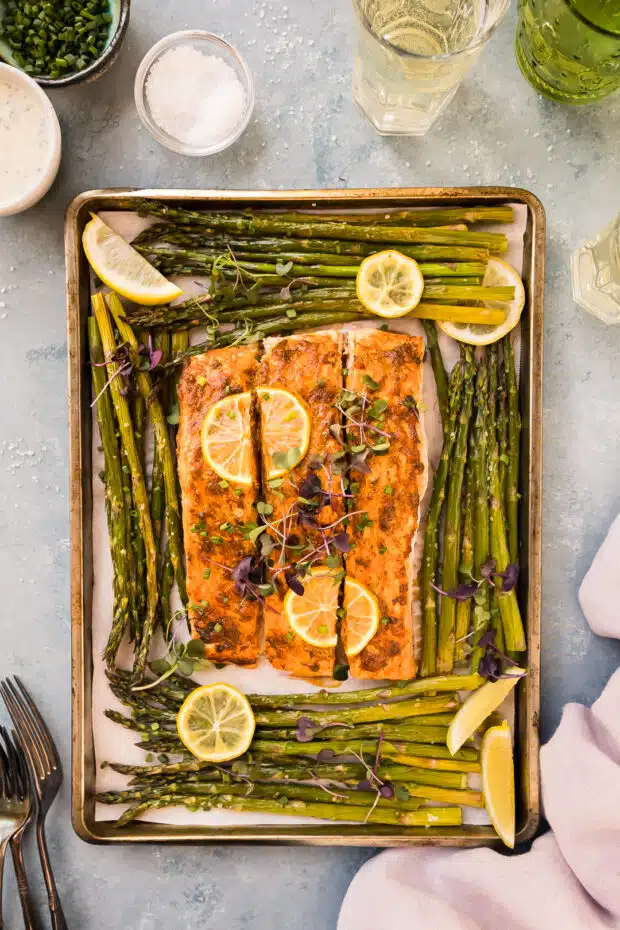 Overhead photo of baked lemon salmon with asparagus on a sheet pan. 