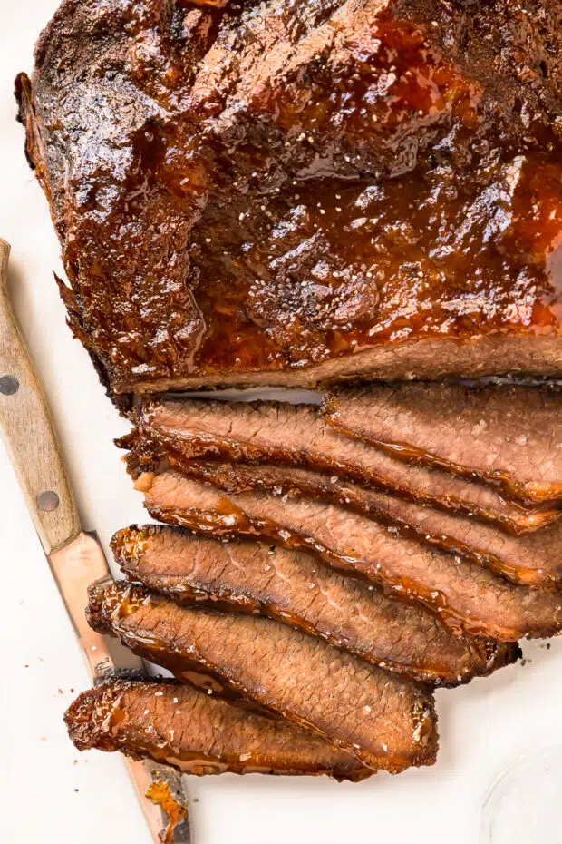 Overhead close-up photo of Slow Cooker Brisket of beef brushed with a BBQ glaze and thinly sliced. 