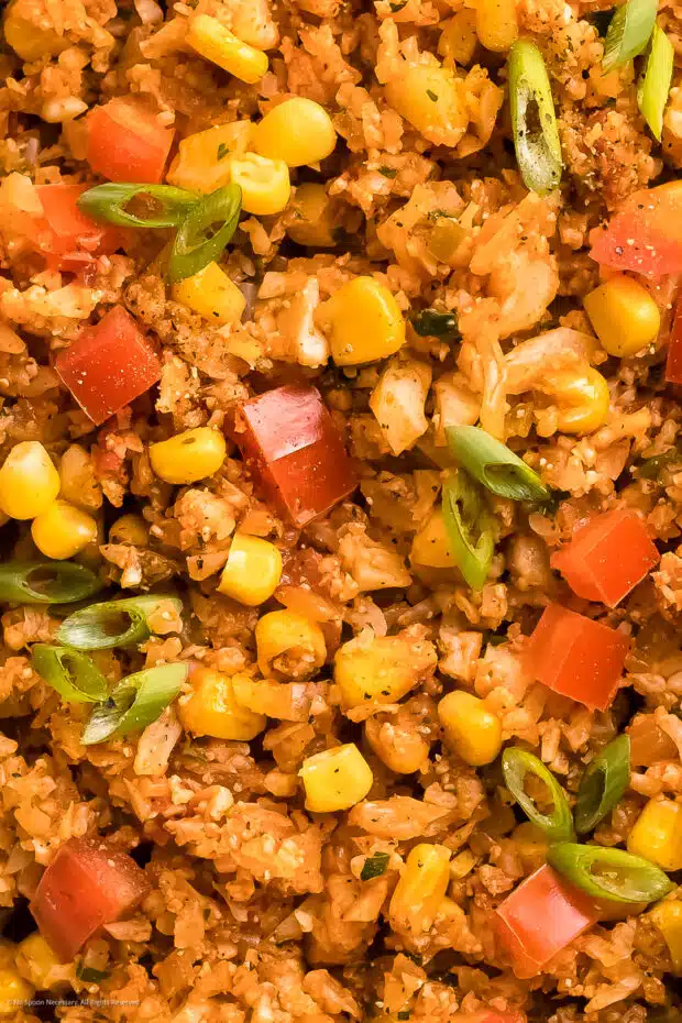 Close-up photo of Mexican rice cauliflower with corn, tomatoes, and onions.