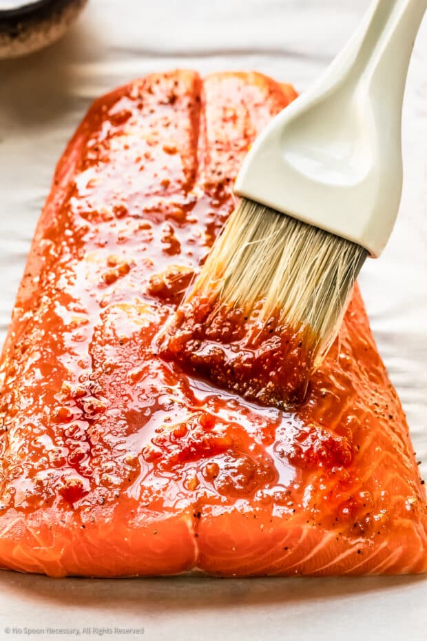 Action photo of sriracha honey glaze being brushed on a side of salmon.