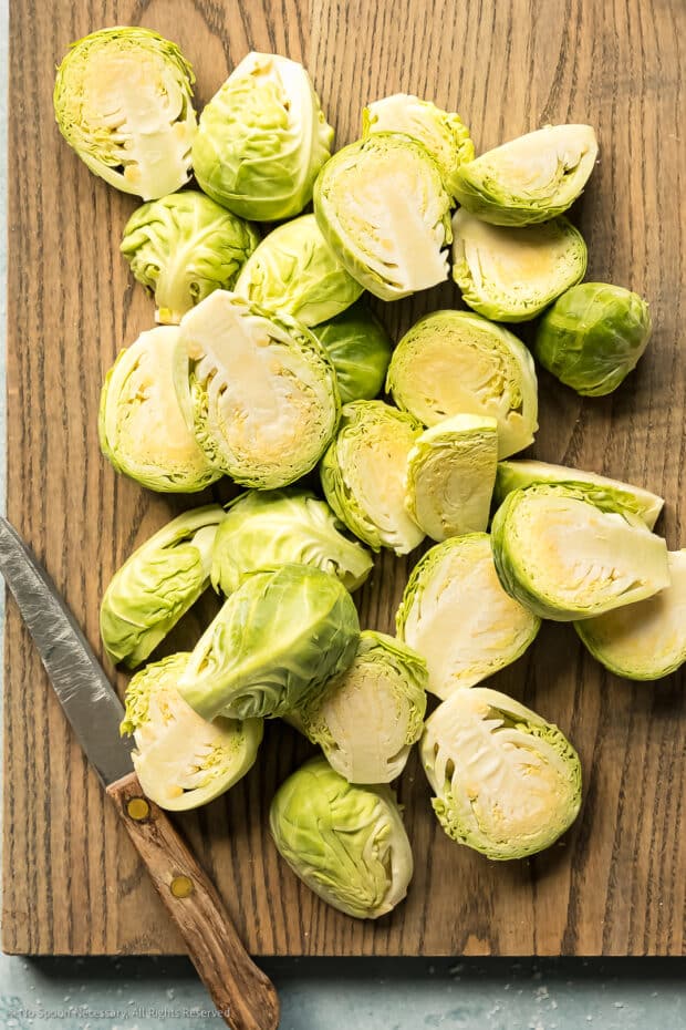 Photo of chopped fresh brussels sprouts on a wood cutting board.