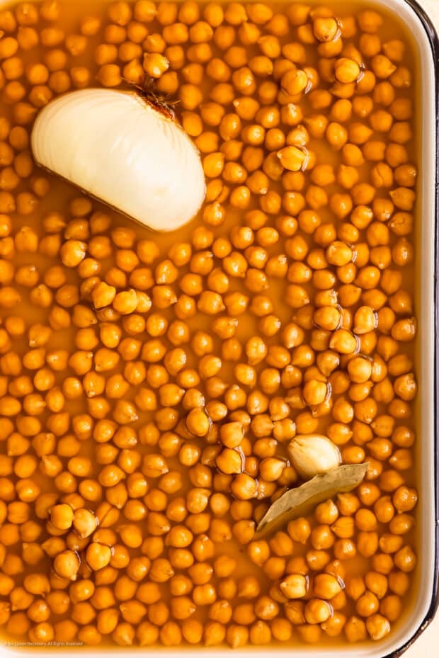 Overhead photo of a tray filled with plump chickpeas and aquafaba made in the slow cooker.