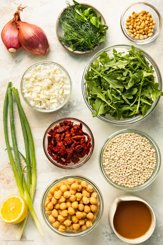 Overhead photo of all the ingredients for pearl Israeli couscous recipe organized in individual bowls.