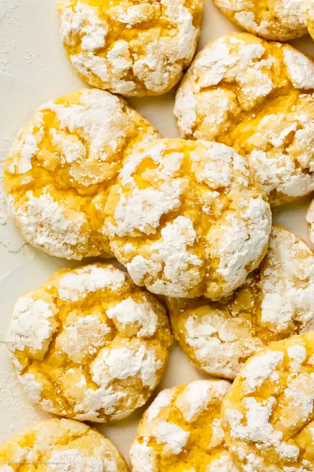 Overhead photo of lemon cake mix crinkle cookies dusted with confectioner's sugar stacked on top of each other.