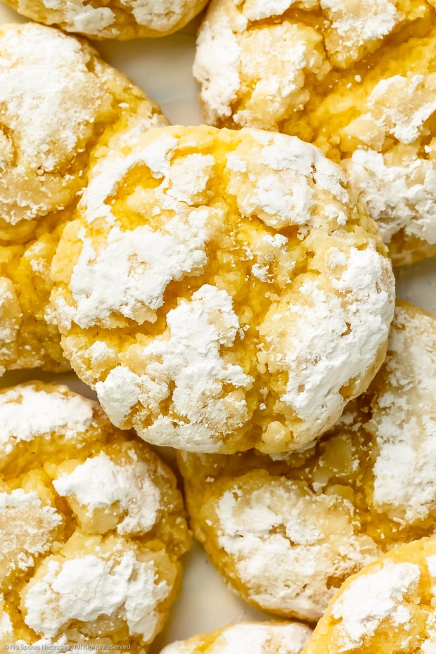 Overhead, close-up photo of a stack of baked lemon cookie with a thick, crinkly coating of powdered sugar.