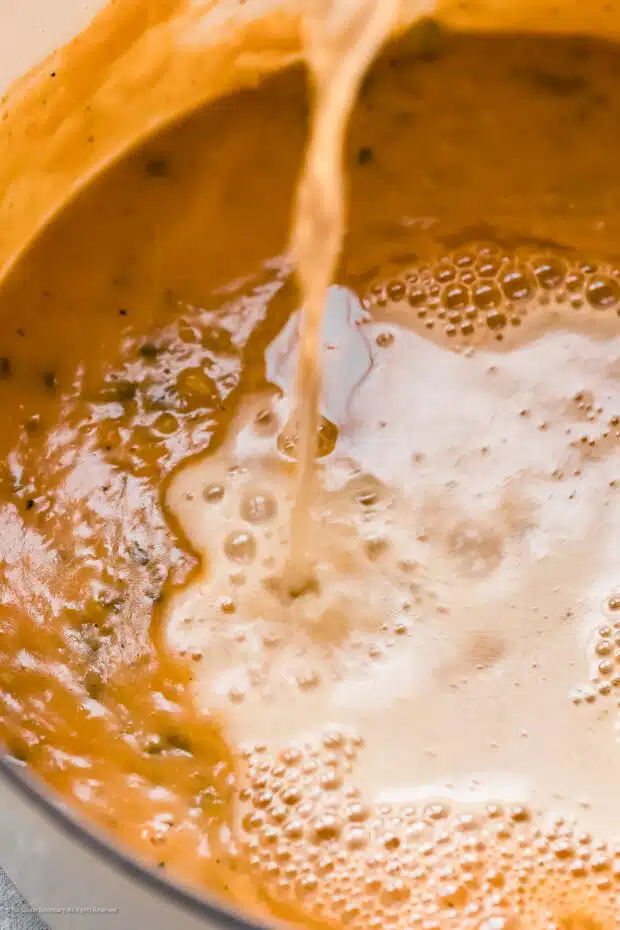 Angled action photo of beer being poured into a soup.