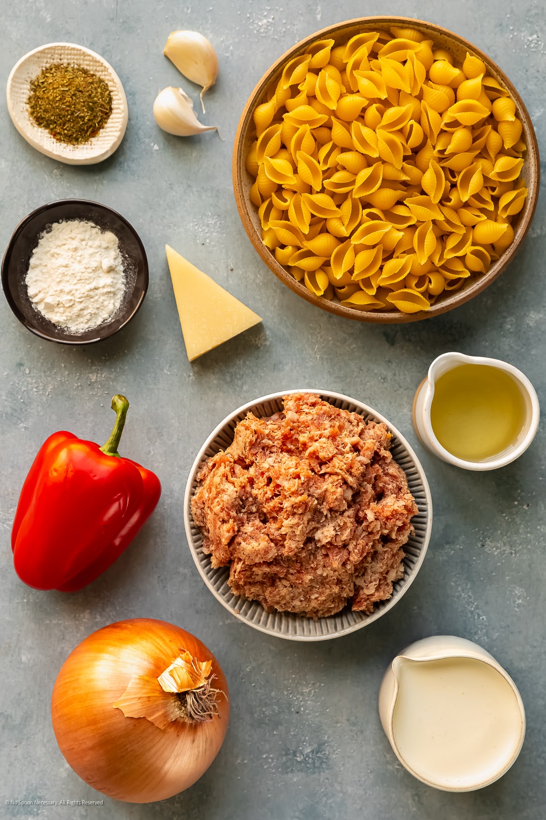 Overhead photo of 10 ingredients needed to make creamy italian sausage pasta neatly arrange on a kitchen counter.