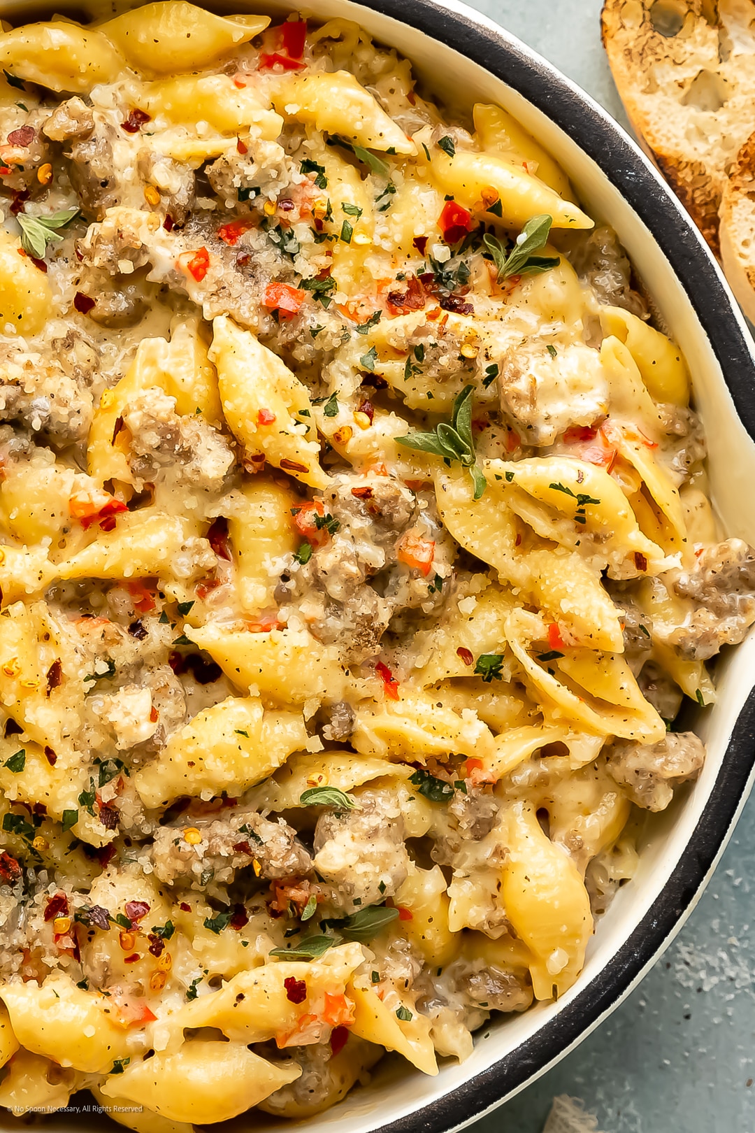 Close-up photo of creamy pasta with sausage and peppers in a skillet.