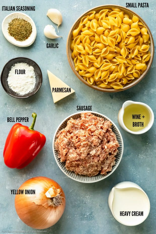 Overhead photo of all the ingredients needed to make sausage pasta neatly organized by individual ingredient with the ingredient name written out. 