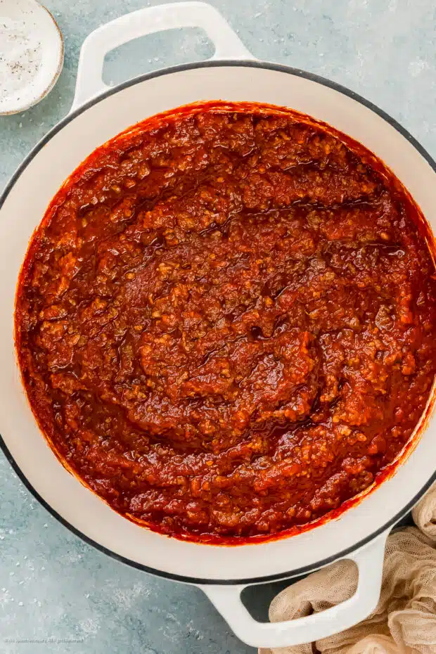 Overhead photo of homemade tomato sauce with Italian sausage in a large pot.