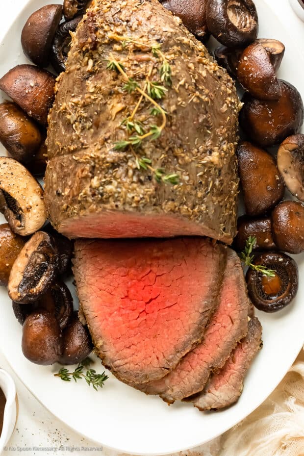 Overhead, close-up photo of a partially sliced roast beef eye round.
