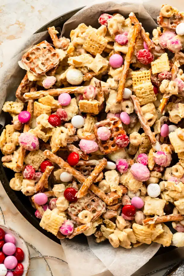 Overhead photo of a serving suggestion for chex mix sweet recipes - in a parchment lined cookie tin wrapped with sparkly twine. 